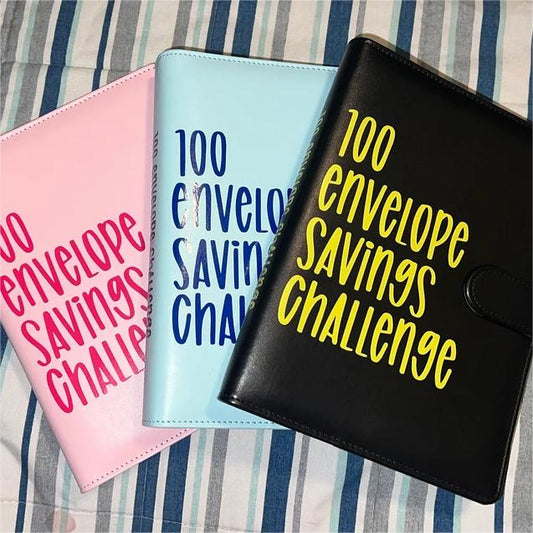 Drei Sparbücher "100 Envelope Savings Challenge" in Rosa, Blau und Schwarz auf gestreiftem Hintergrund.