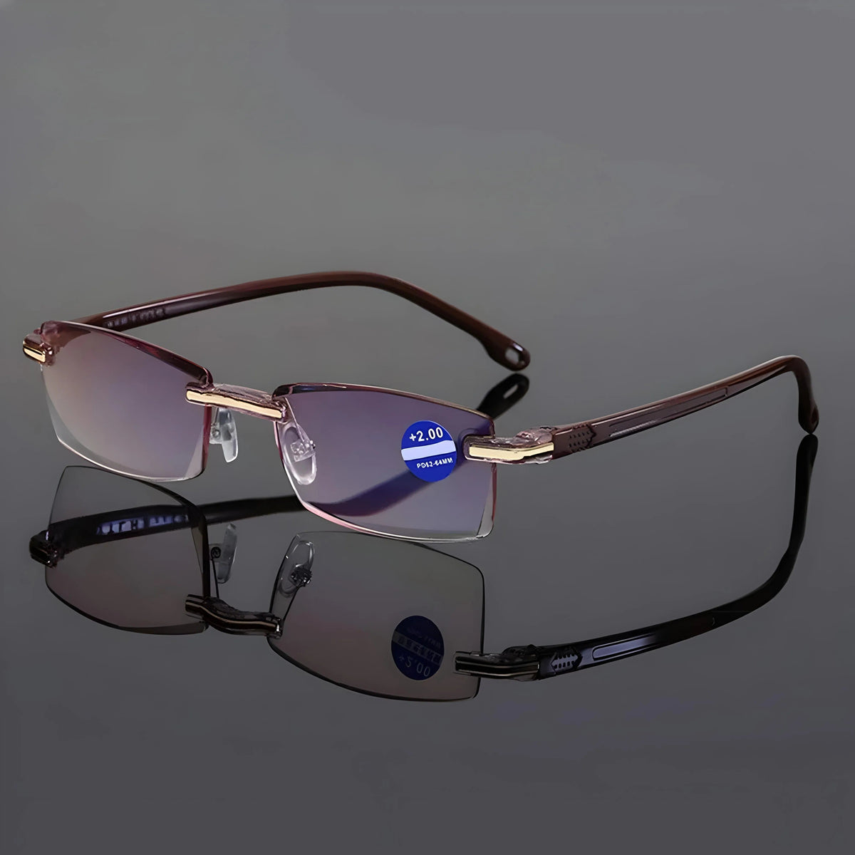 Randlose Lesebrille in der braunen Bügelvariante mit goldfarbenen Scharnieren auf spiegelnder grauer Fläche. 7