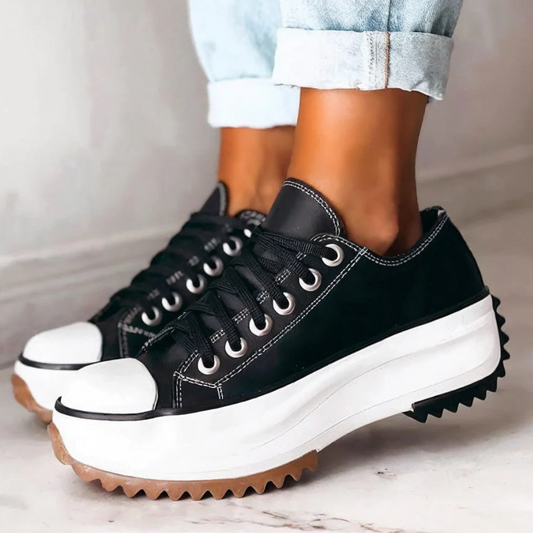 Schwarze Plateau-Sneaker aus Leder, Damen, modisch, lässig, robuste Sohle, Jeanshintergrund.