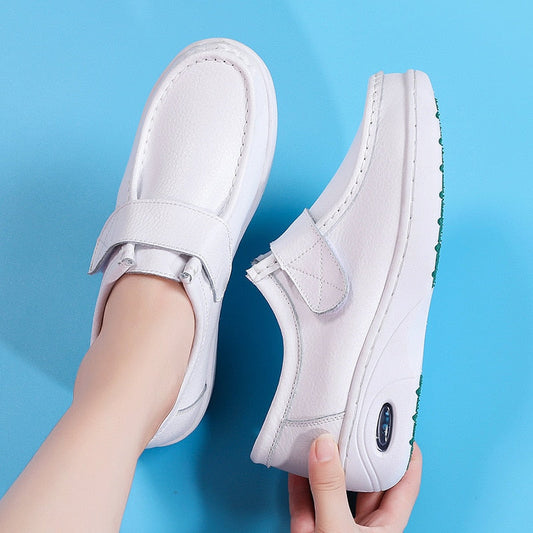 Weiße Damen-Lederslipper mit Klettverschluss, bequeme Freizeitschuhe auf blauem Hintergrund.