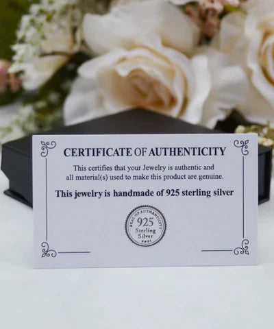 Zertifikat für 925 Sterling Silber Schmuck, handgefertigt, vor Blumenarrangement.