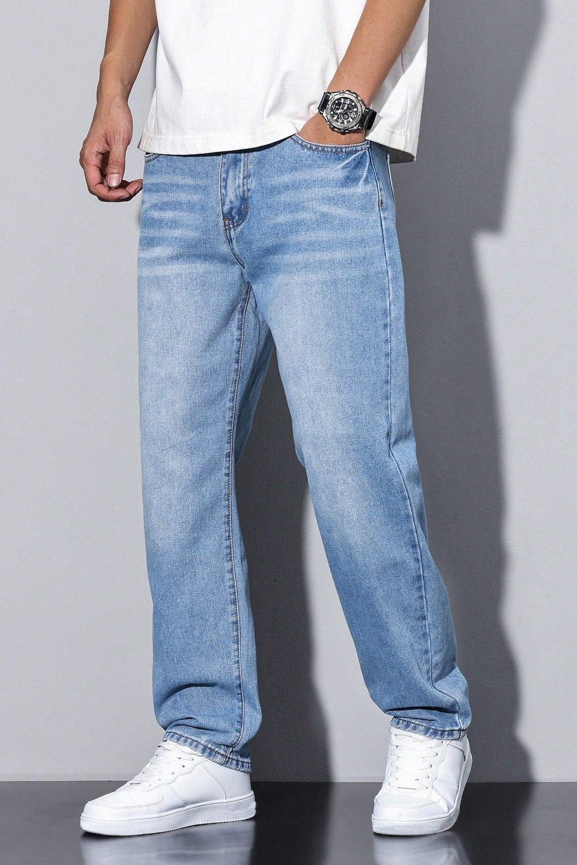 Jeans mit geradem Bein in hellblauer Waschung, getragen zu weißem Shirt, Armbanduhr und weißen Sneakern 8