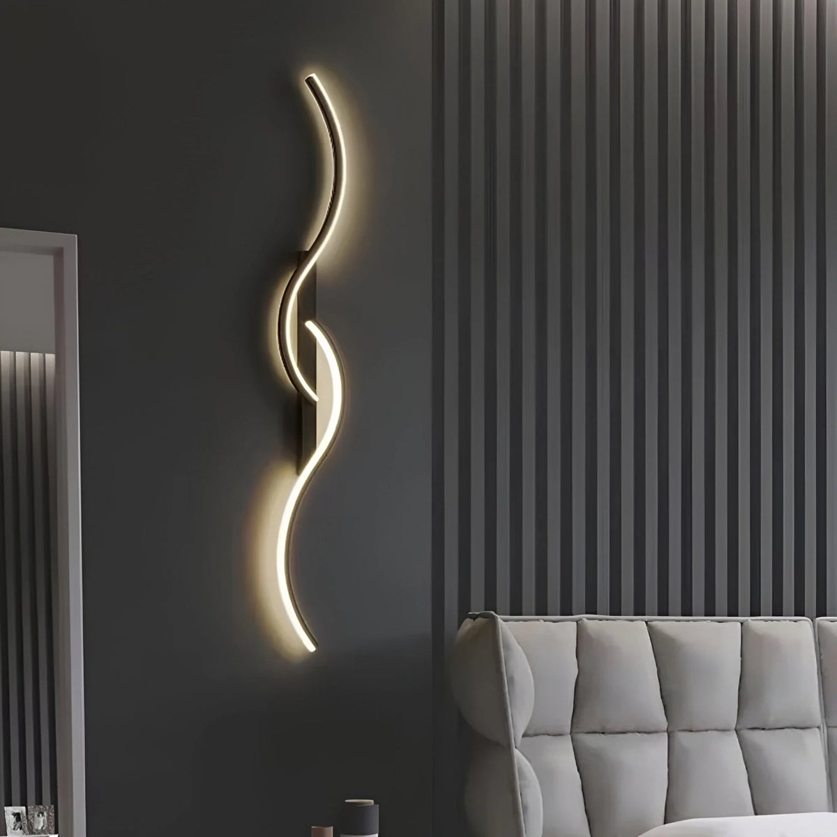 Schwarze Wellenlampe leuchtet an dunkelgrauer Wand neben grauem gepolstertem Sofa 6