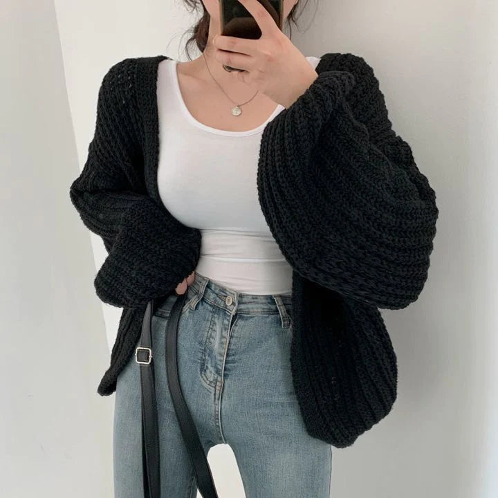 Frau trägt schwarzes Strickweste, weiße Bluse, blaue Jeans, modisch, bequem, Damenmode.