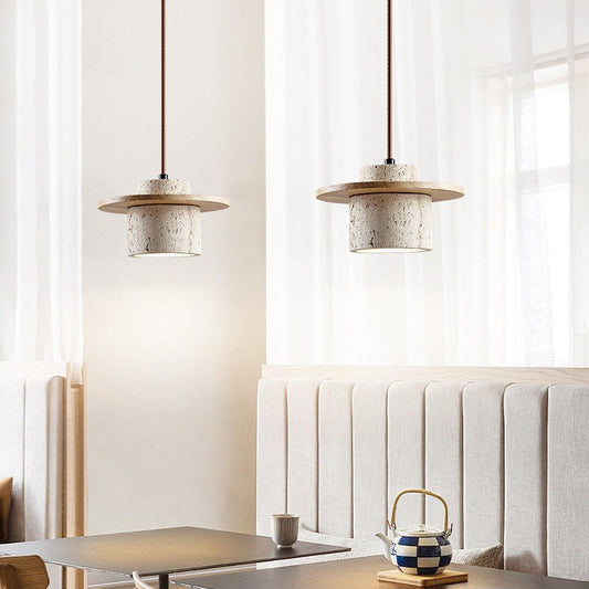 Zwei moderne Hängelampen aus Beton über einem Esstisch in minimalistischem Café-Interieur.