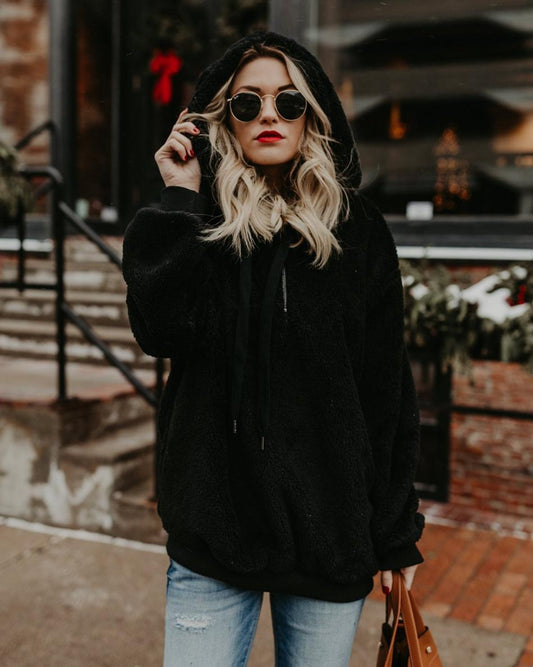 Frau in schwarzem Kapuzenpullover, Sonnenbrille, rote Lippen, lässiger Winterlook, Straße.