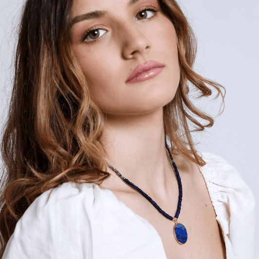 Frau mit blauem Edelstein-Halskette, weißes Kleid, Modeaccessoire, eleganter Schmuck.