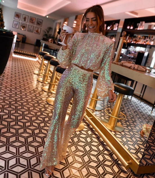 Frau in glitzerndem Paillettenkleid, Barhocker, Cocktail, stilvolle Abendmode, glamouröses Outfit.