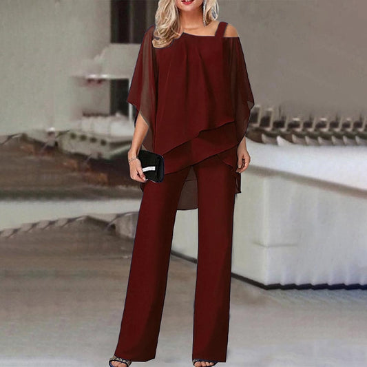 Frau in eleganter, weinroter Chiffon-Hose und Bluse, Abendmode, schulterfrei, mit schwarzer Clutch.