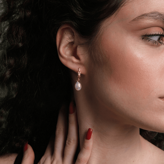 Frau mit Perlenohrring, goldene Fassung, elegante Mode, Nahaufnahme, roter Nagellack.