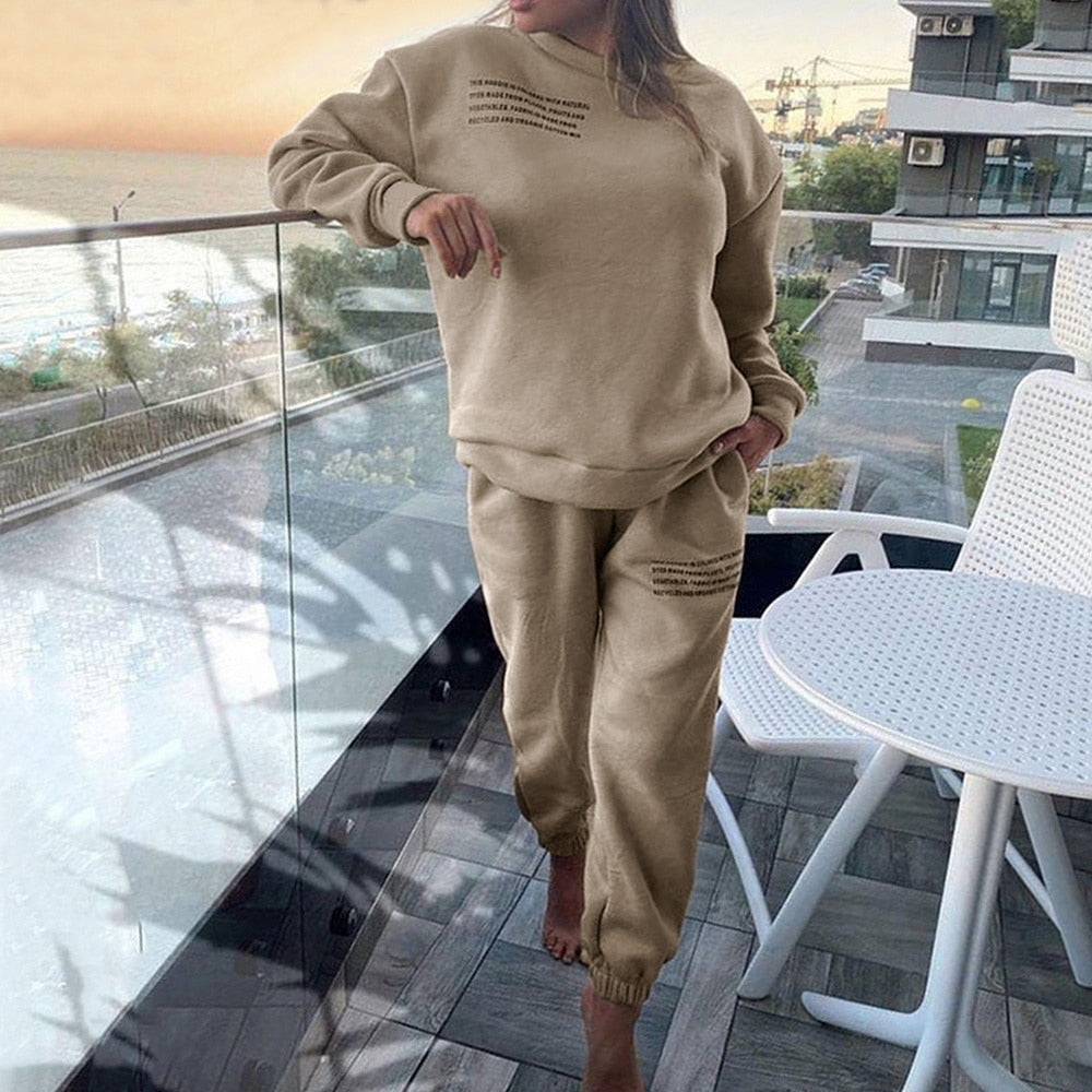 Frau in beigem Jogginganzug auf Balkon, Freizeitmode, komfortabel, lässig, urbaner Stil.