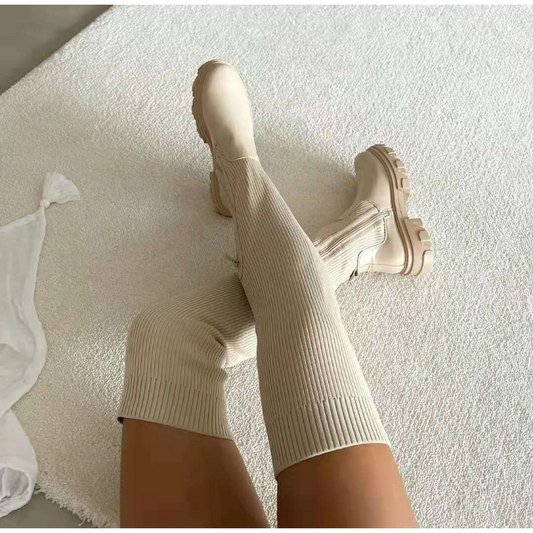 Beige kniehohe Stiefel auf Teppich, modisch, gerippt, Damenmode, Herbst-Winter-Trend.