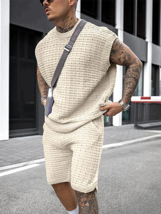 Mann in cremefarbenem Strick-Set, ärmelloses Oberteil und Shorts, urbaner Stil, Sommermode.