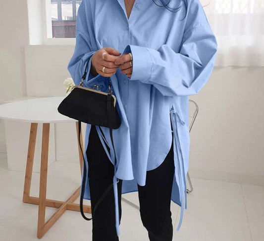 Frau in blauer Oversize-Bluse, schwarze Tasche, moderne Mode, lässiger Stil, Innenraum.