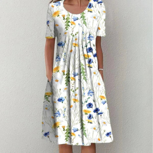 Frau in weißem Blumenkleid mit blauen und gelben Blumen, Sommermode, knielang, kurzärmelig.