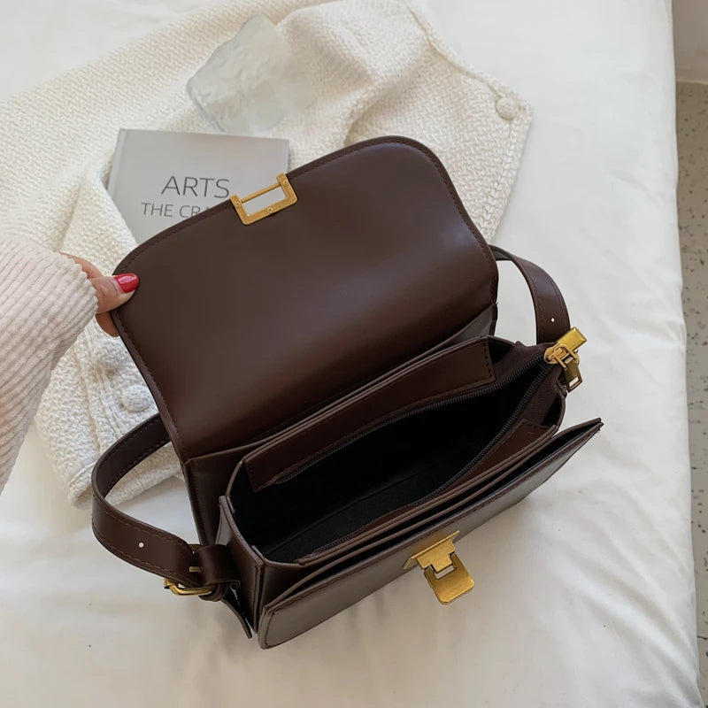 Braune Lederhandtasche mit goldenen Verschlüssen auf weißem Bett, stilvoll und elegant.