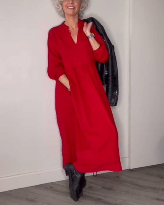 Ältere Frau in rotem Kleid mit schwarzer Lederjacke, lächelnd, modisch, elegant, Holzfußboden.