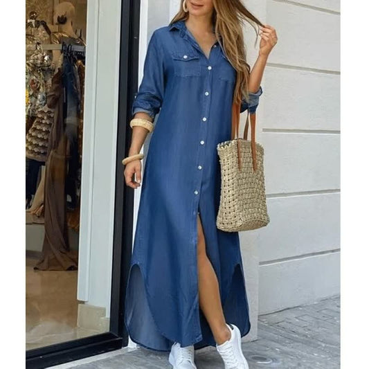 Frau in blauem Jeanskleid mit Knopfleiste, trägt Strohtasche, weiße Sneaker, lässiger Look.