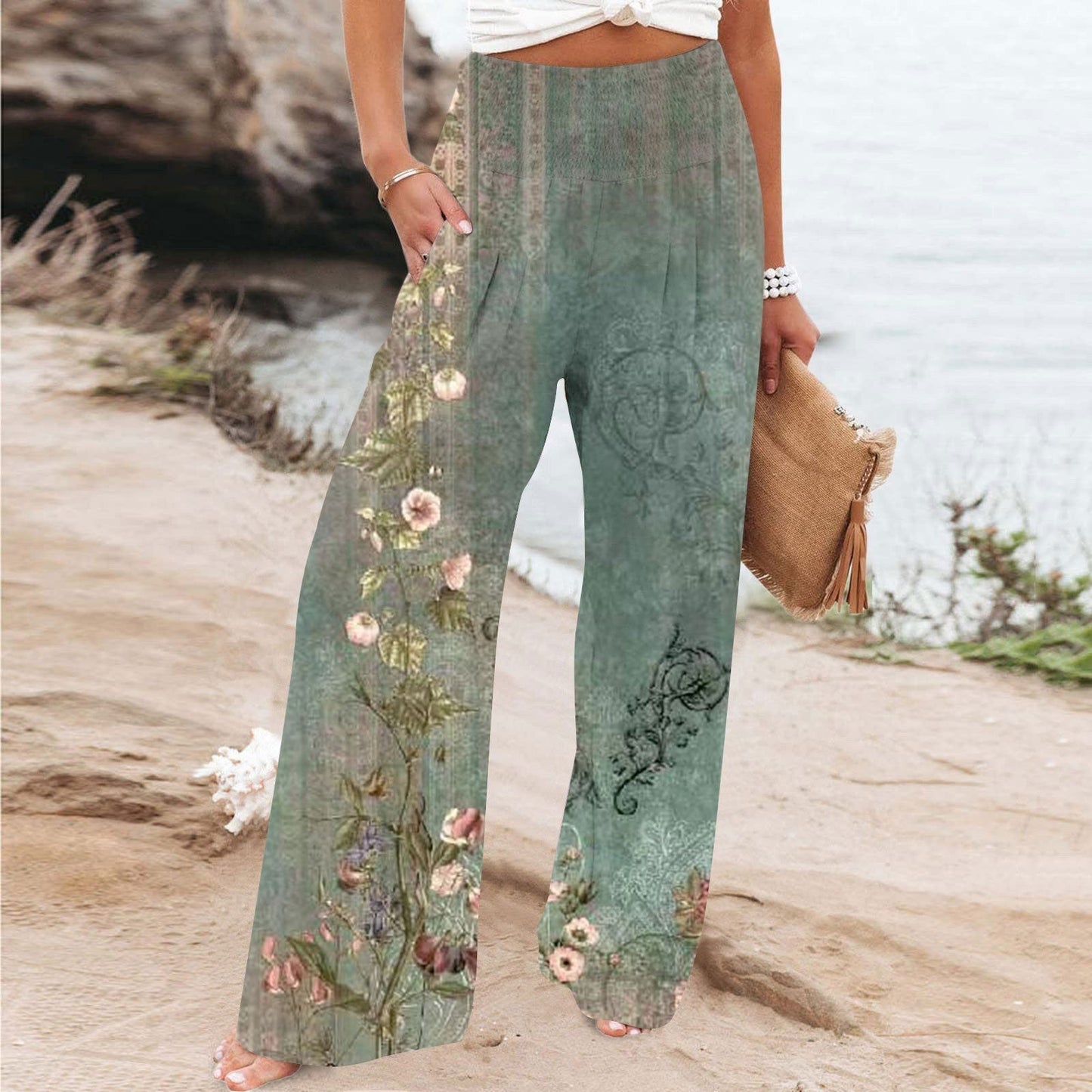 Frau in grüner, bedruckter High-Waist-Hose am Strand, modische Freizeitkleidung.