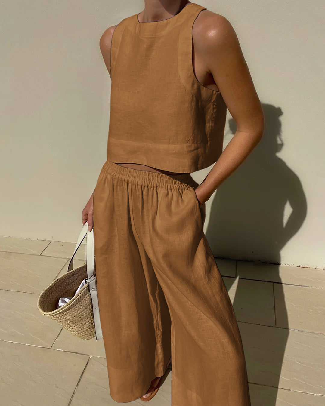 Frau in braunem Leinen-Zweiteiler mit Strohtasche, Sommermode, lässiger Stil.