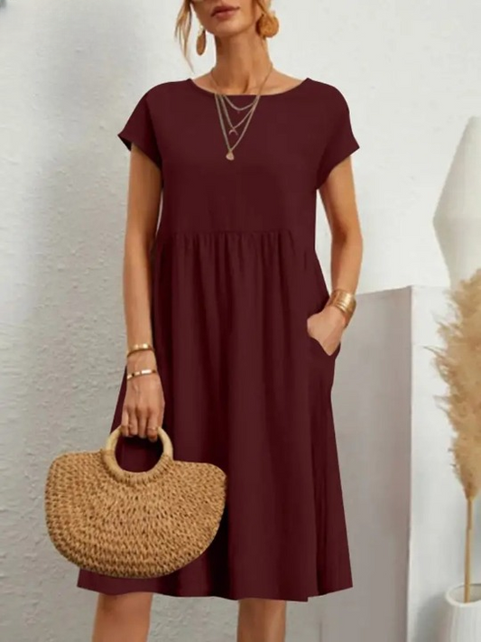 Frau in burgunderrotem Sommerkleid mit Strohtasche, elegantes Outfit, Modeaccessoires.