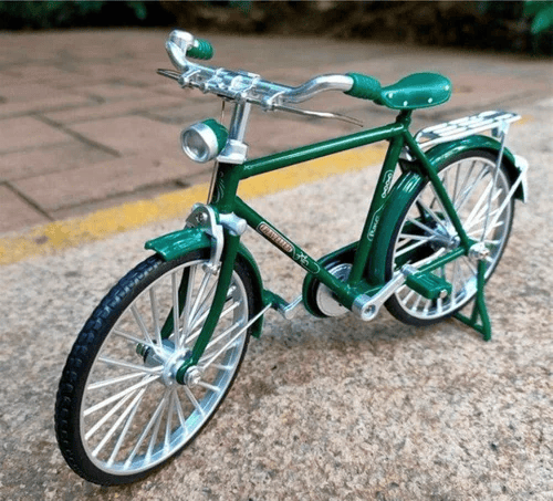 Grünes Miniaturfahrrad aus Metall, detailgetreu, auf Gehweg platziert.