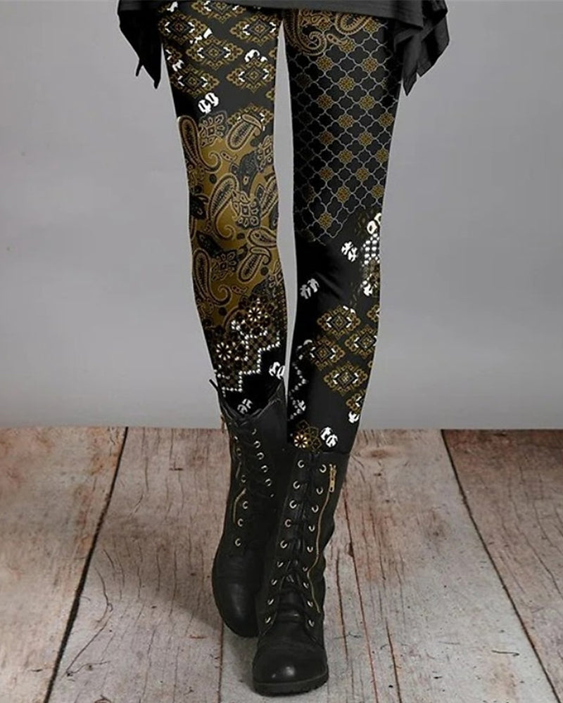 Damen Leggings mit Paisley-Muster, schwarz-gold, kombiniert mit schwarzen Stiefeln.