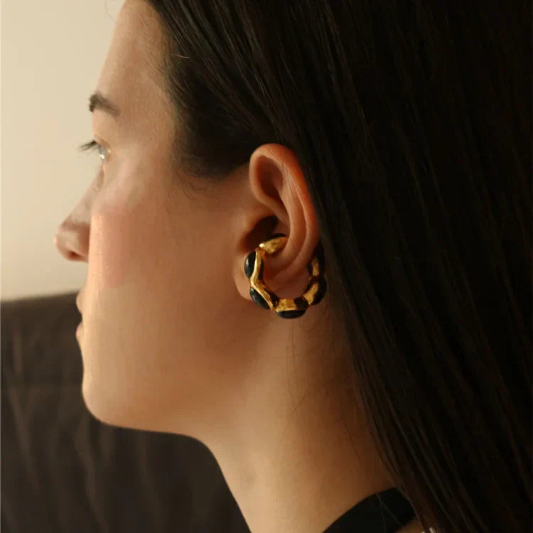 Frau mit gold-schwarzem Ohrring, modisches Accessoire, Nahaufnahme, seitliches Profil.