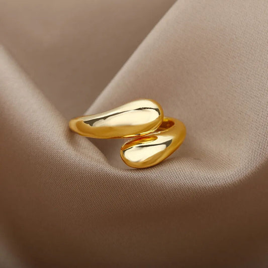 Goldener, geschwungener Ring auf beigem Stoff, elegantes Schmuckdesign, glänzend, modern.