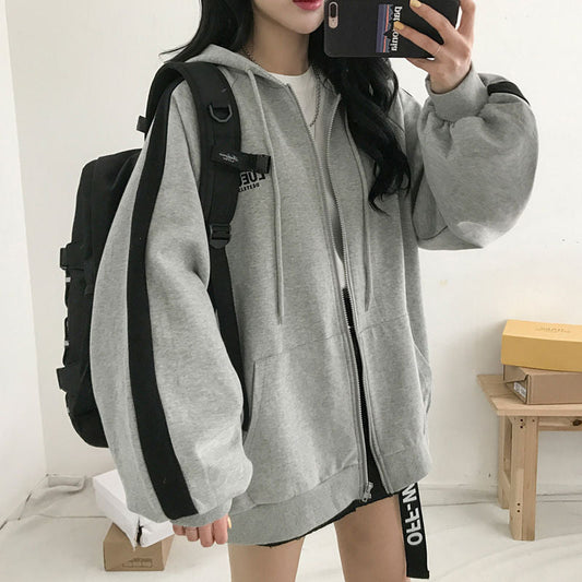 Frau in grauem Kapuzenpullover mit schwarzen Streifen und Rucksack, modisch, lässig.