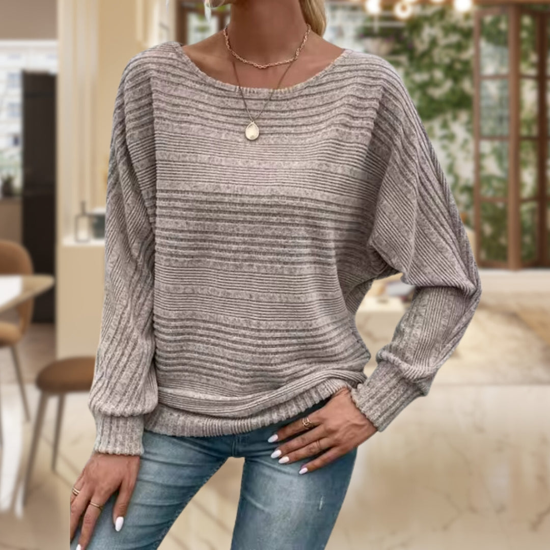 Frau in grauem Strickpullover und Jeans in modernem Wohnzimmer.