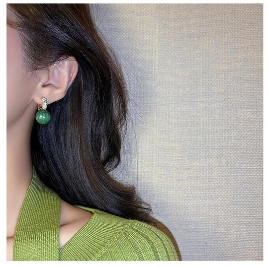 Frau mit grünem Ohrring, elegantes Design, Schmuck, Modeaccessoire, Nahaufnahme.
