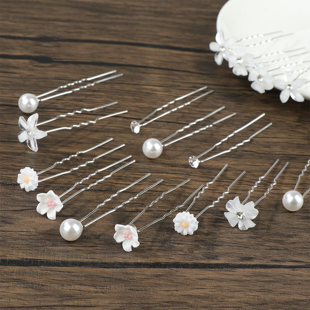 Haarpins mit weißen Blumen und Perlen auf Holztisch, Hochzeit Haarschmuck, elegant und stilvoll.