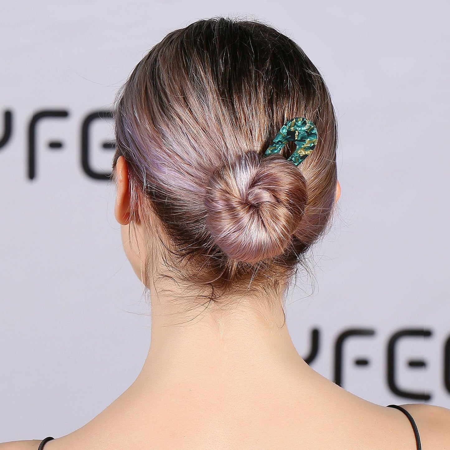 Frau mit Dutt und grünem Haarschmuck, eleganter Haarstil, Rückansicht, glattes Haar.