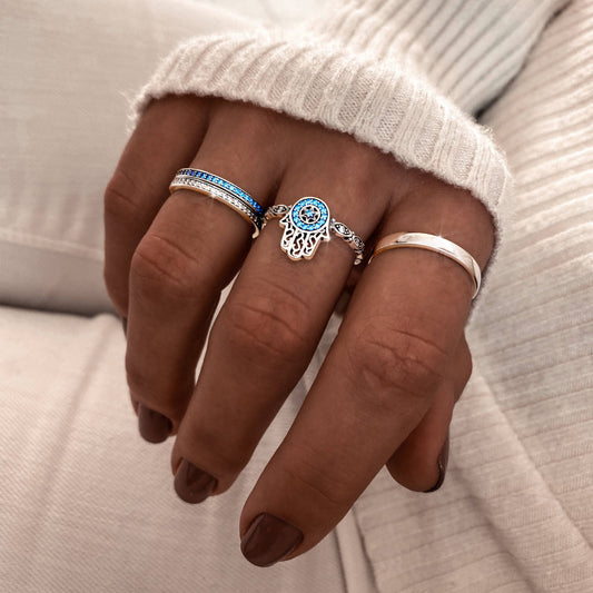 Drei Silberringe an Hand, Hamsa-Design, blauer Stein, Damenmode, Schmuck, Nahaufnahme.