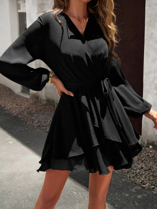 Frau in schwarzem Wickelkleid mit langen Ärmeln, elegantes Design, draußen stehend.