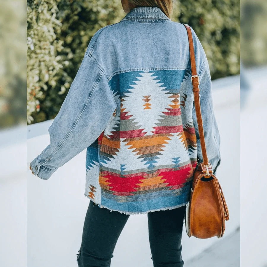 Frau in Jeansjacke mit Aztekenmuster und brauner Ledertasche im Freien.