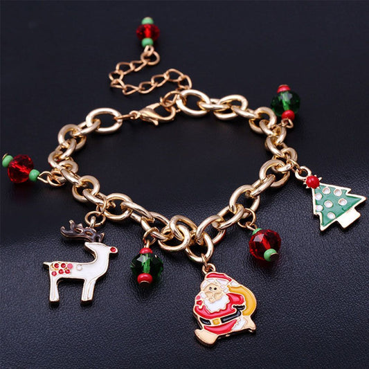 Goldenes Weihnachtsarmband mit Rentier, Weihnachtsmann und Tannenbaum-Anhängern auf schwarzem Hintergrund.