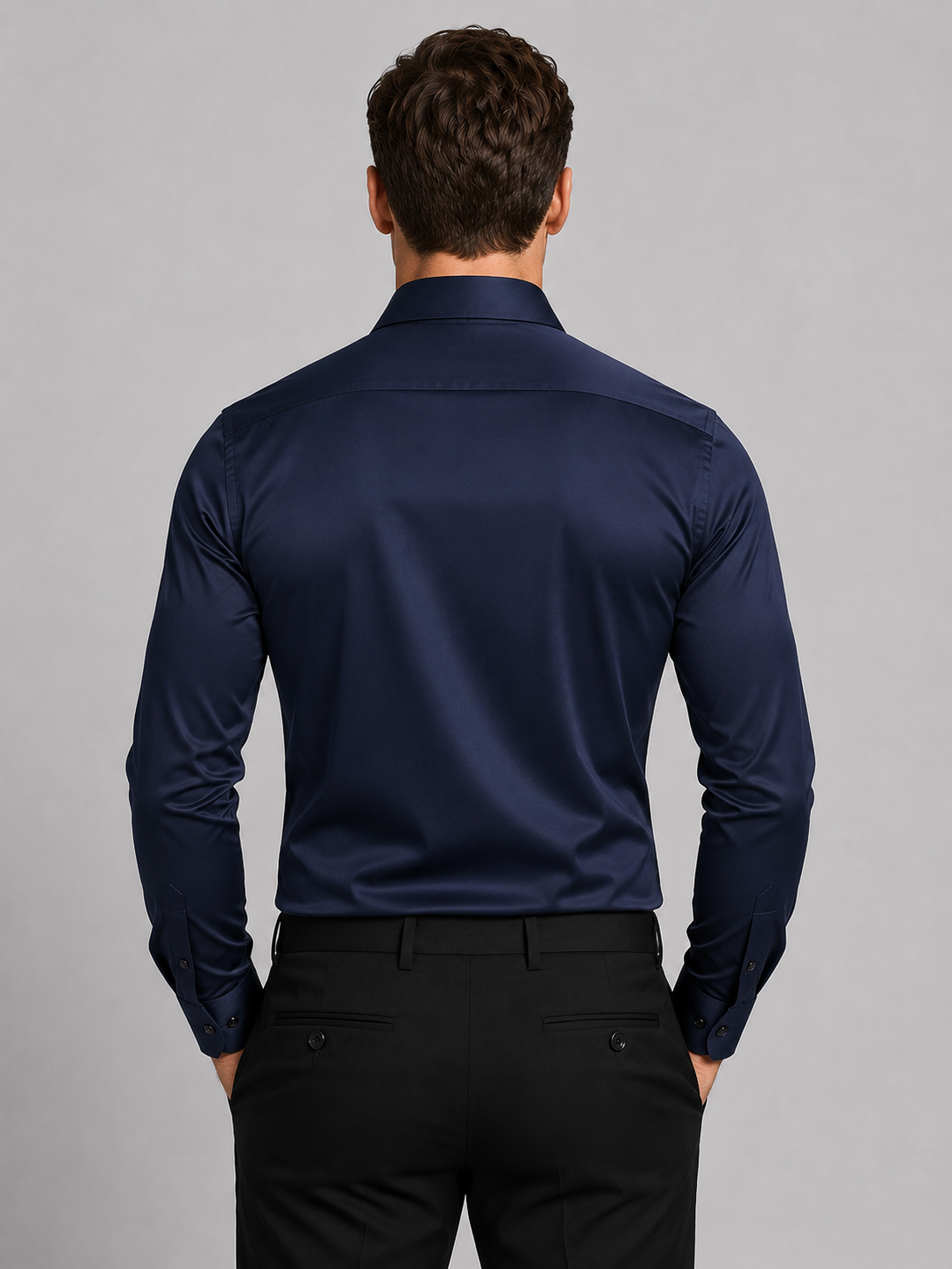 Rückansicht des marineblauen Hemds am Model: glatter Rücken mit Passe, geknöpfte Manschetten, dazu schwarze Hose mit Paspeltaschen. 6