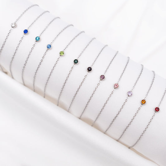 Silberne Geburtsstein-Armbänder auf weißem Hintergrund, verschiedene Farben, Schmuck für Damen.