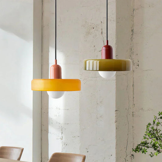 Zwei moderne Hängelampen aus Glas in Gelb und Grün vor weißer Wand, skandinavisches Design.