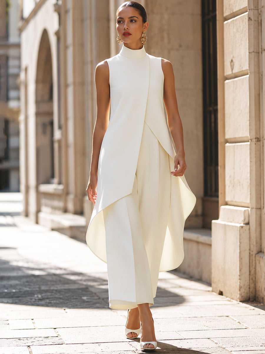 Model in cremeweißem Set beim Gehen durch eine Gasse, das asymmetrische Oberteil schwingt locker über der weiten Hose. 9