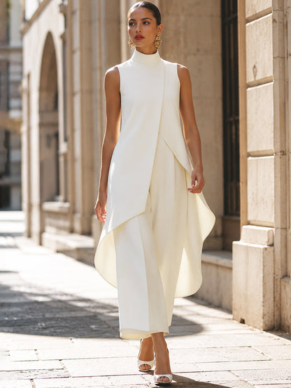Model in cremeweißem Set beim Gehen durch eine Gasse, das asymmetrische Oberteil schwingt locker über der weiten Hose. 9