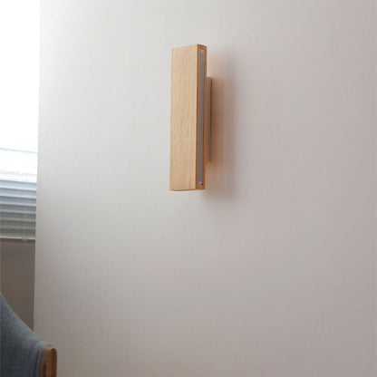 Seitenansicht der ausgeschalteten Wandlampe aus hellem Holz, senkrecht montiert neben einem Fenster mit Jalousie. 2