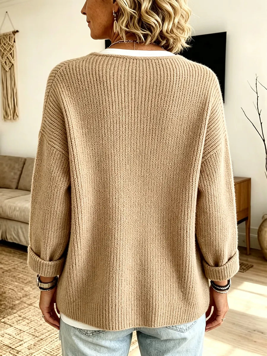 Rückansicht der sandfarbenen Strickjacke mit durchgehender Rippstruktur, breiten Schultern und umgeschlagenen Ärmelbündchen 2
