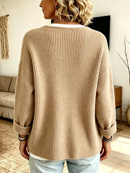 Rückansicht der sandfarbenen Strickjacke mit durchgehender Rippstruktur, breiten Schultern und umgeschlagenen Ärmelbündchen 2