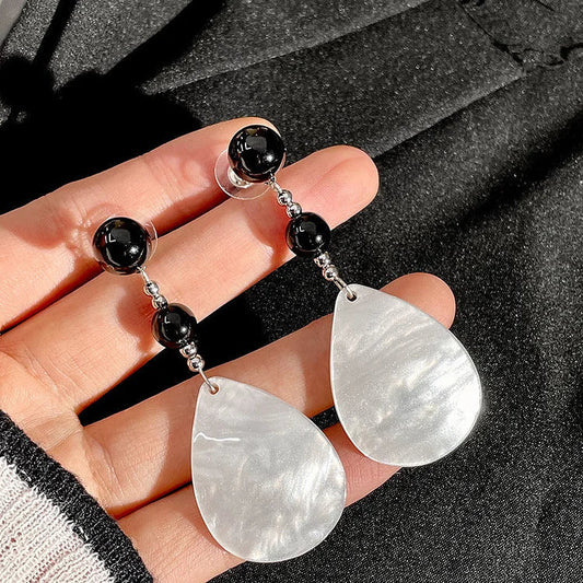 Schwarze und weiße Tropfenohrringe aus Perlmutt, handgehalten, eleganter Schmuck.