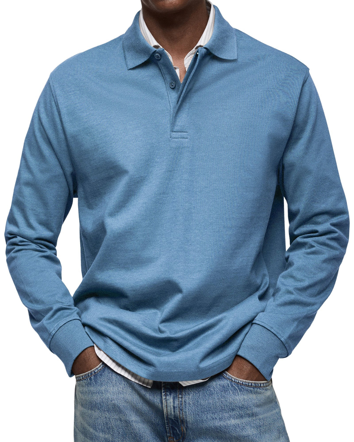 Frontansicht des Langarm-Poloshirts in Hellblau am Model, Hände in den Taschen, gestreiftes Hemd darunter. 2