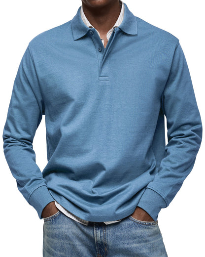 Frontansicht des Langarm-Poloshirts in Hellblau am Model, Hände in den Taschen, gestreiftes Hemd darunter. 2