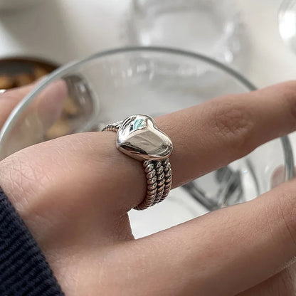 Silberner Herzring auf Finger, elegantes Schmuckdesign, glänzend, modisch, Damenaccessoire.